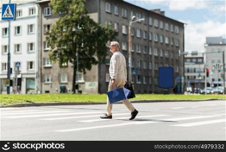 sale, traffic and people concept - senior man with shopping bags walking along city crosswalk. senior man with shopping bags walking on crosswalk