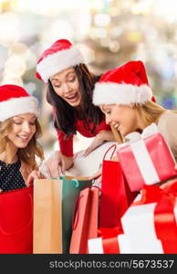 sale, winter holidays, christmas and people concept - smiling young woman in santa helper hat with gifts and shopping bags over lights background