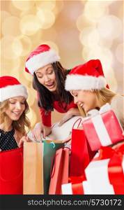 sale, winter holidays, christmas and people concept - smiling young woman in santa helper hat with gifts and shopping bags over beige lights background