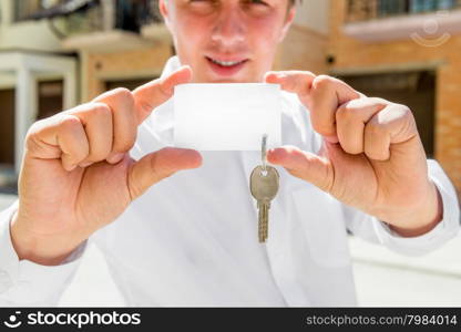 Sales Agent of apartments holds the key in his hand. space on the card for an inscription