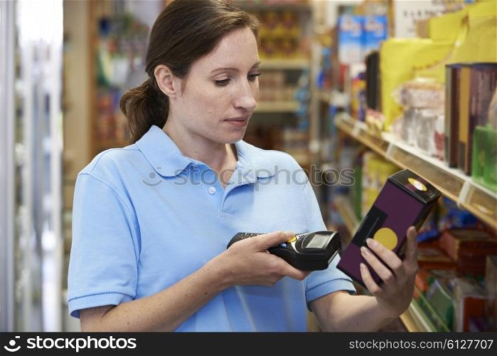 Sales Assistant Checking Stock Levels In Supmarket Using Hand Held Device