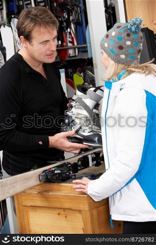 Sales Assistant Helping Advising Female Customer On Ski Boots In Hire Shop