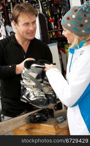 Sales Assistant Helping Advising Female Customer On Ski Boots In Hire Shop