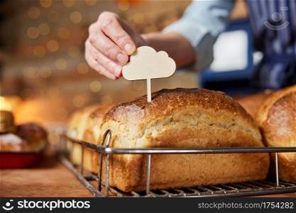 Sales Assistant In Bakery Putting Blank Label Into Freshly Baked Baked Sourdough Loaves Of Bread