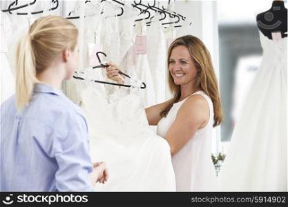Sales Assistant In Bridal Store Helping Bride To Choose Wedding Dress