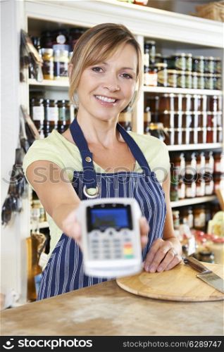 Sales Assistant In Food Store Handing Credit Card Machine To Customer