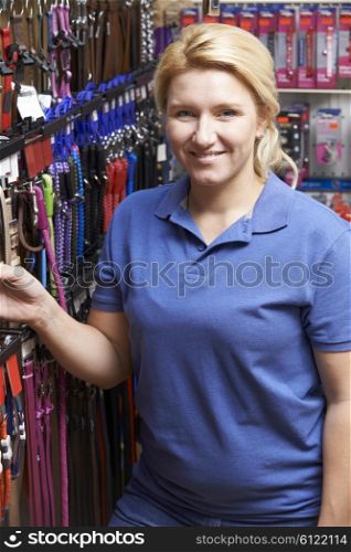 Sales Assistant In Pet Store With Display Of Dog Leashes