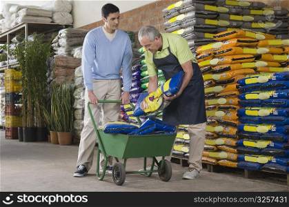 Sales clerk arranging fertilizer&acute;s bag in shopping cart