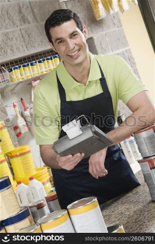Sales clerk holding adding machine and smiling