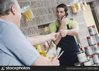 Sales clerk talking on the telephone and giving a credit card to a customer
