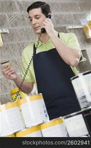 Sales clerk talking on the telephone and holding a credit card