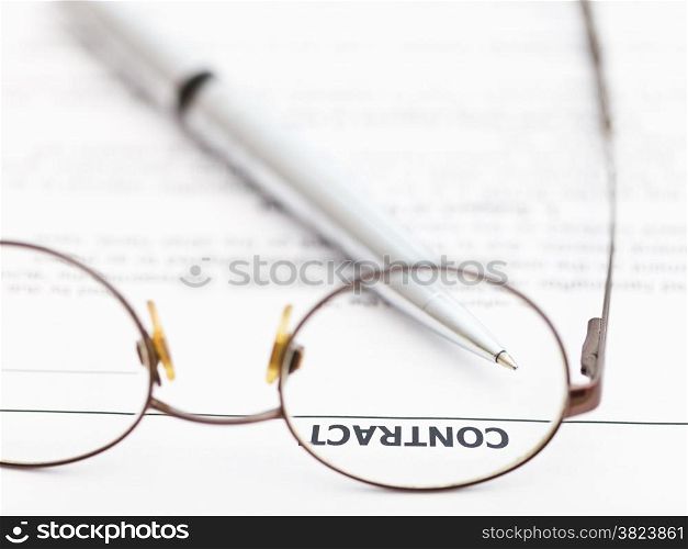sales contract and silver pen through spectacles