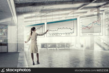 Sales dynamics report mixed media. Elegant businesswoman in modern office drawing infographs