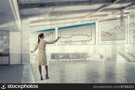 Sales dynamics report mixed media. Elegant businesswoman in modern office drawing infographs