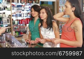 Sales Person Assisting Female Shoppers in Choice of Cosmetics