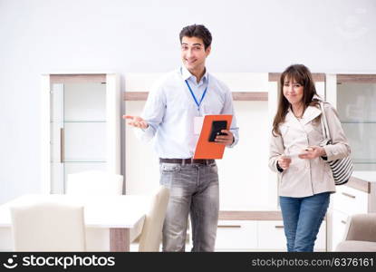 Salesman explaining to woman customer at furniture store