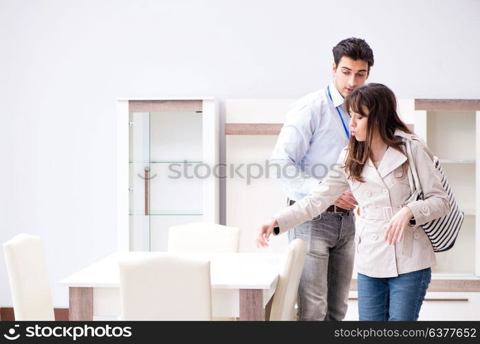 Salesman explaining to woman customer at furniture store