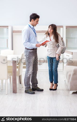 Salesman explaining to woman customer at furniture store