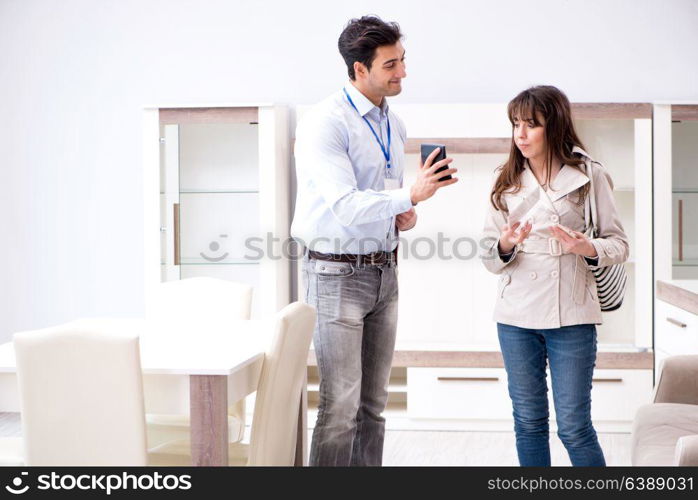 Salesman explaining to woman customer at furniture store