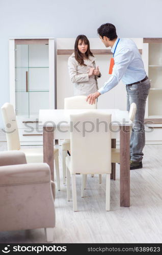 Salesman explaining to woman customer at furniture store