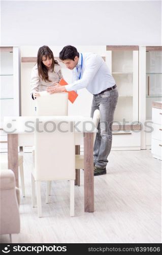 Salesman explaining to woman customer at furniture store