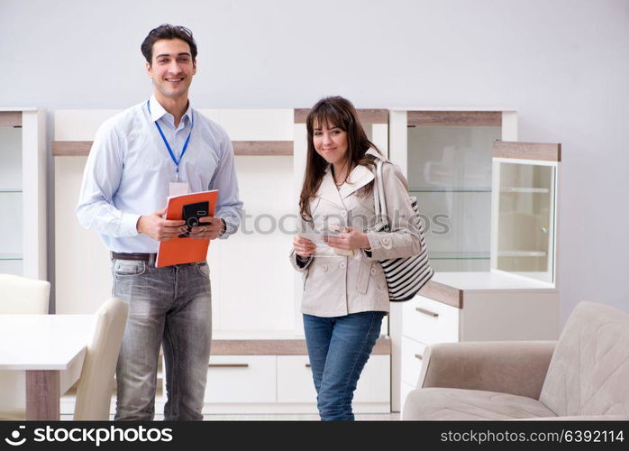 Salesman explaining to woman customer at furniture store