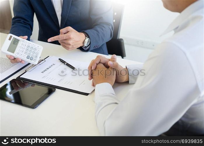 salesman holding a key and calculating a price at the dealership office to buyer for car insurance price