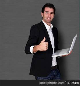 Salesman holding laptop computer and showing thumb up