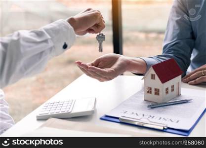 Salesman house brokers provide key to new homeowners in office.