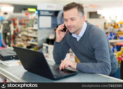 salesman talking on smartphone while looking at laptop