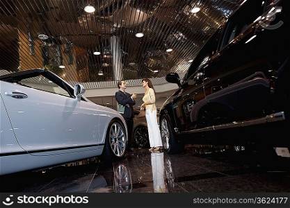 Salesman talking to woman in automobile showroom