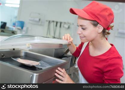 saleswoman working with sliced meat at the supermarket