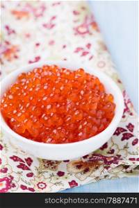 Salmon caviar in white bowl on light background, selective focus
