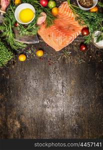 Salmon fillet and ingredients for cooking on dark rustic wooden background, top view. Healthy food cooking concept.