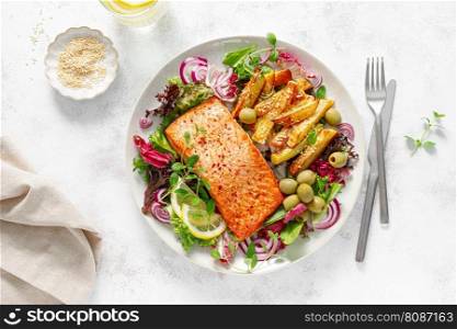 Salmon fillet grilled, fried potato and fresh vegetable green salad, top view