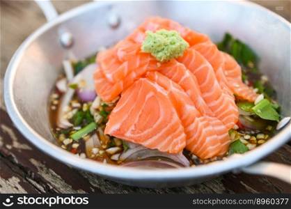 salmon fillet with wasabi on spicy sauce , fresh raw salmon salad on wooden table - Thai food