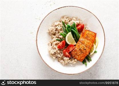 Salmon fish fillet baked, rice, green beans and tomatoes in lunch bowl. Healthy food, top view