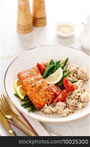 Salmon fish fillet baked, rice, green beans and tomatoes in lunch bowl. Healthy food