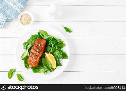 Salmon fish fillet grilled and fresh spinach salad on plate for lunch. Top view