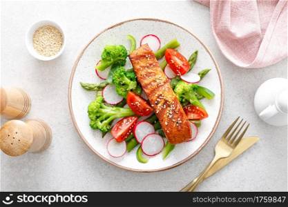 Salmon fish fillet grilled and vegetable salad with radish, tomato, green pepper, broccoli and asparagus.