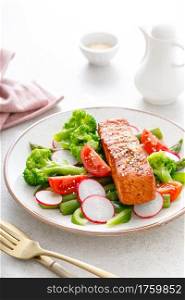 Salmon fish fillet grilled and vegetable salad with radish, tomato, green pepper, broccoli and asparagus.