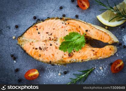 Salmon fish fillet steak seafood / Grilled salmon steak with herbs and spices rosemary lemon on dark background , top view