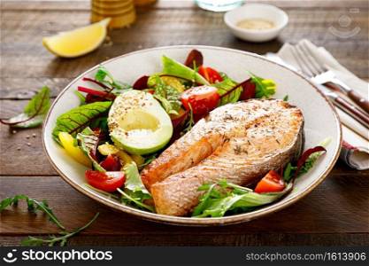 Salmon fish steak grilled, avocado and fresh vegetable salad with tomato, bell pepper and leafy vegetables