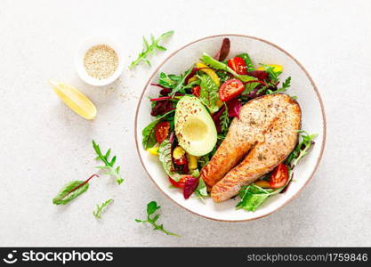 Salmon fish steak grilled, avocado and fresh vegetable salad with tomato, bell pepper and leafy vegetables