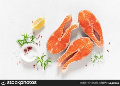 Salmon. Fresh raw salmon fish steaks with cooking ingredients, herbs and lemon on white background, top view