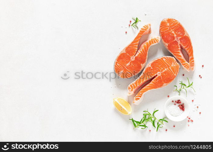 Salmon. Fresh raw salmon fish steaks with cooking ingredients, herbs and lemon on white background, top view