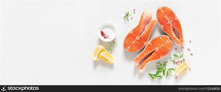 Salmon. Fresh raw salmon fish steaks with cooking ingredients, herbs and lemon on white background, top view, banner