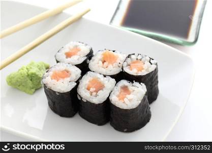 Salmon Maki sushi with chopsticks and soy sauce in white background