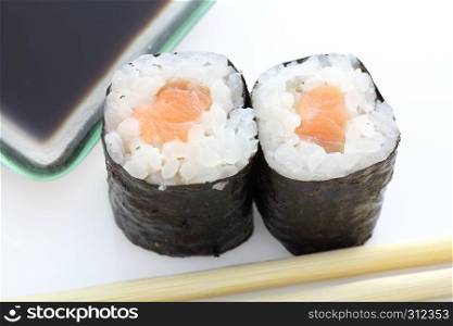 Salmon Maki sushi with chopsticks and soy sauce in white background