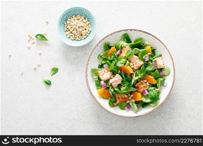 Salmon orange salad with pine nuts, red onion and corn salad. Top view